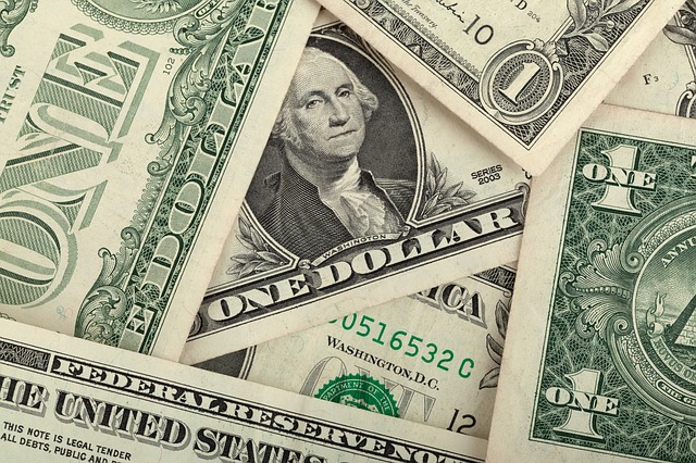Fanned stack of US dollar bills representing the high cost of enterprise database software licensing